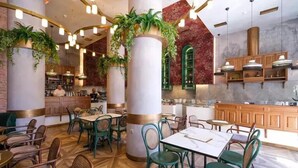 A restaurant with green chairs and tables, large columns with plants, and a marble wall. - Belle Athenes - Luxury Rooms at Monastiraki Railway Station (Athens)