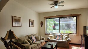 Ein Wohnzimmer mit zwei Sofas, einem Couchtisch, einer TV-Konsole und einem Deckenventilator.