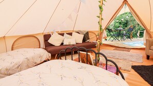 Ein gemütliches Zeltinnere mit einem Bett, einer Couch und einem Essbereich.