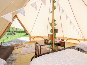 Ein gemütliches Zeltinneres mit einem Bett, einem kleinen Tisch und einem Stuhl.