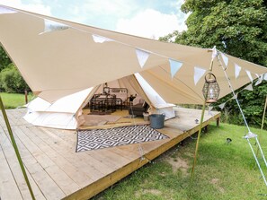 A tent with a wooden deck, a patterned rug, and a metal bucket. - Abercefel Retreat (Llandysul)