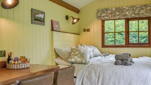 Een gezellige slaapkamer met een bed, een bureau en een raam met uitzicht op groen.