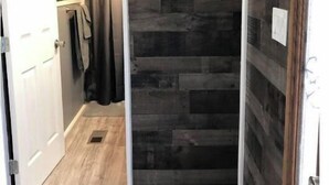 Eine schmale Dusche mit dunklen Holzpaneelen und einer Wanddekoration mit Fischmotiven.