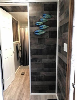 Shower area features a textured wall and decorative leaf elements.