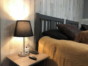 Contemporary bedroom with a dark headboard, bedside table, and a lamp.