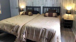 Ein Doppelbett mit zwei Nachttischen, jeder mit einer Lampe, in einem Zimmer mit Holzwandverkleidung.