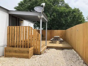 Relax under the pergola, surrounded by lush surroundings, with a wooden bench and picnic table at your disposal.