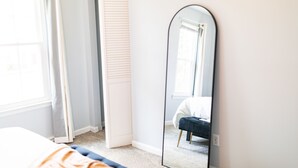 A bedroom with a bed, a mirror, and a window.