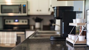 A kitchen with a coffee maker, a microwave, and a coffee dispenser.