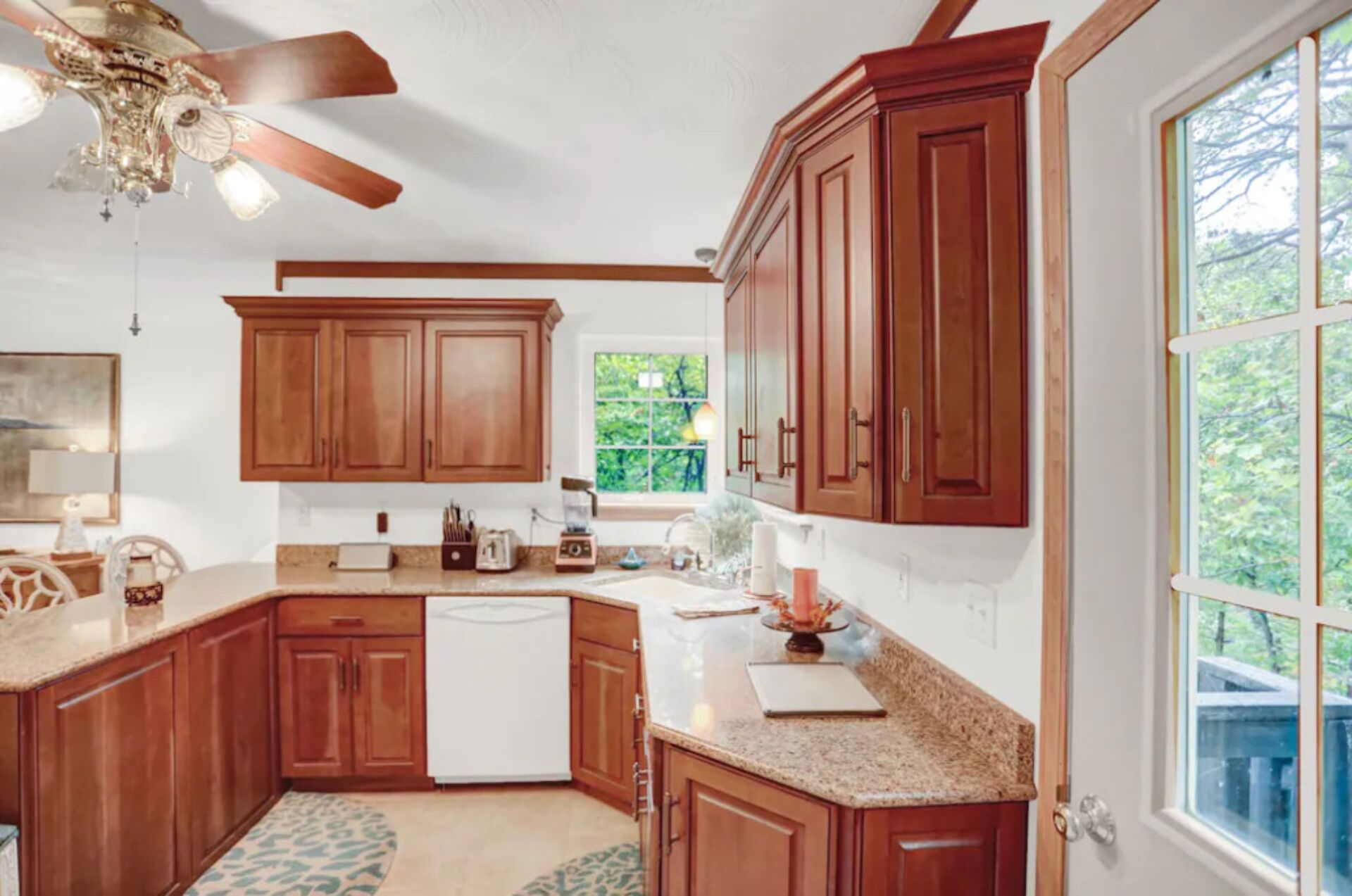 A kitchen with wooden cabinets, a white refrigerator, a granite countertop, and a ceiling fan.