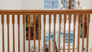 Una scala con ringhiera in legno conduce a una stanza con un'ampia finestra ad arco.