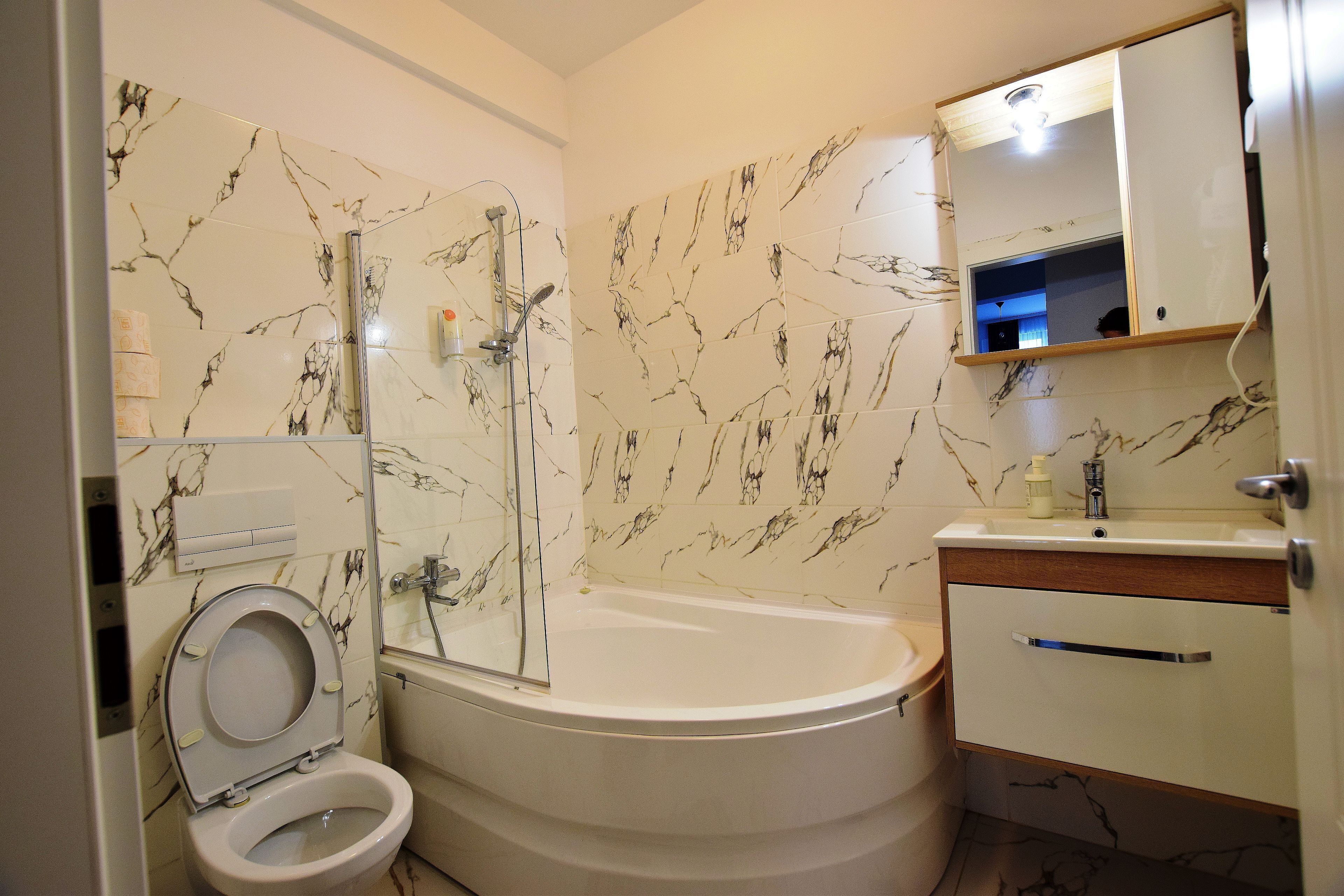 Een badkamer met een toilet, douche, badkuip en wastafel.