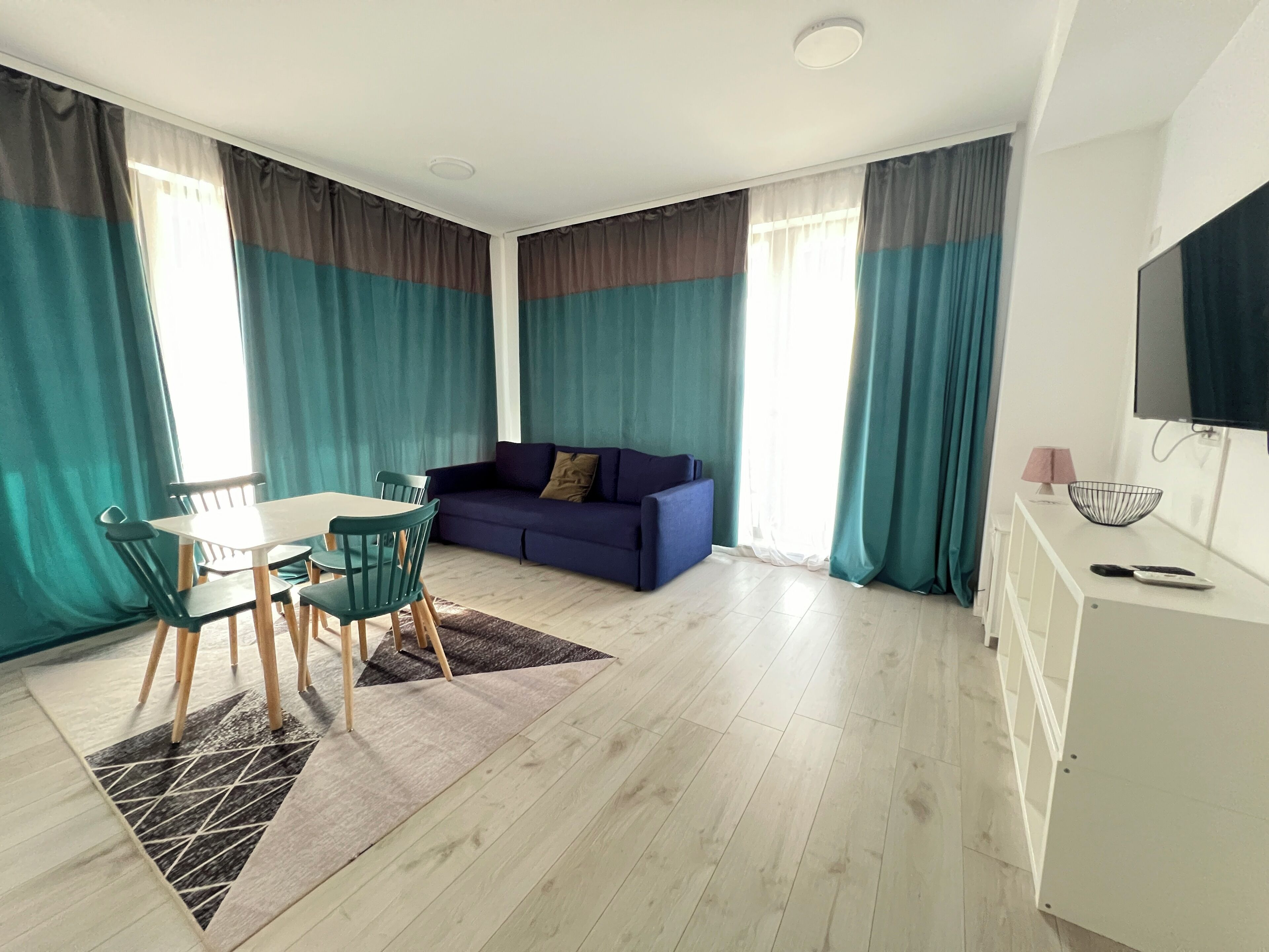 Una sala de estar moderna con comedor, que incluye un sofá, un televisor y una mesa de comedor con sillas.