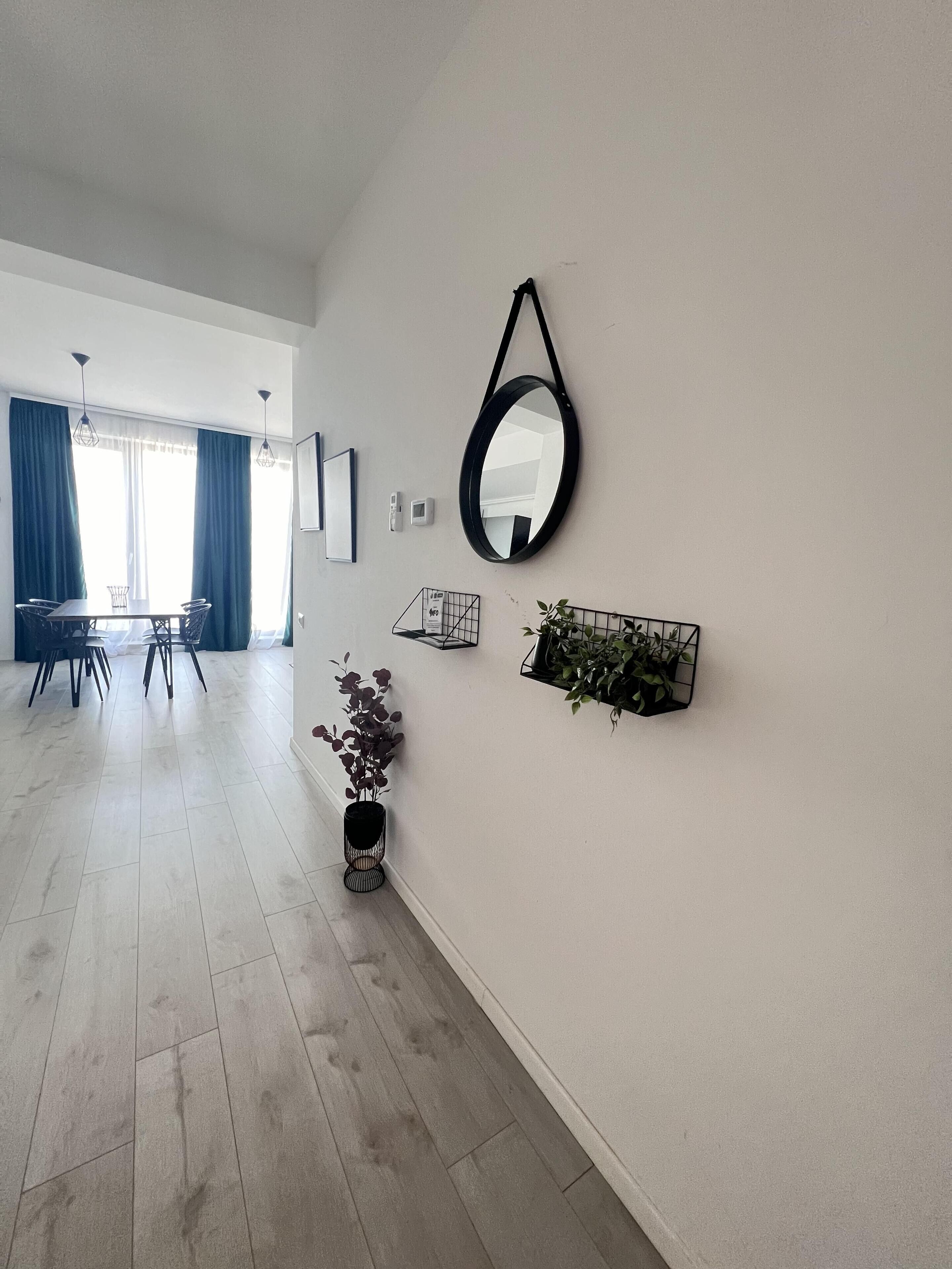 A modern living room with a dining area, a large mirror, and a potted plant.
