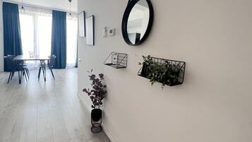 A modern living room with a dining area, a large mirror, and a potted plant.