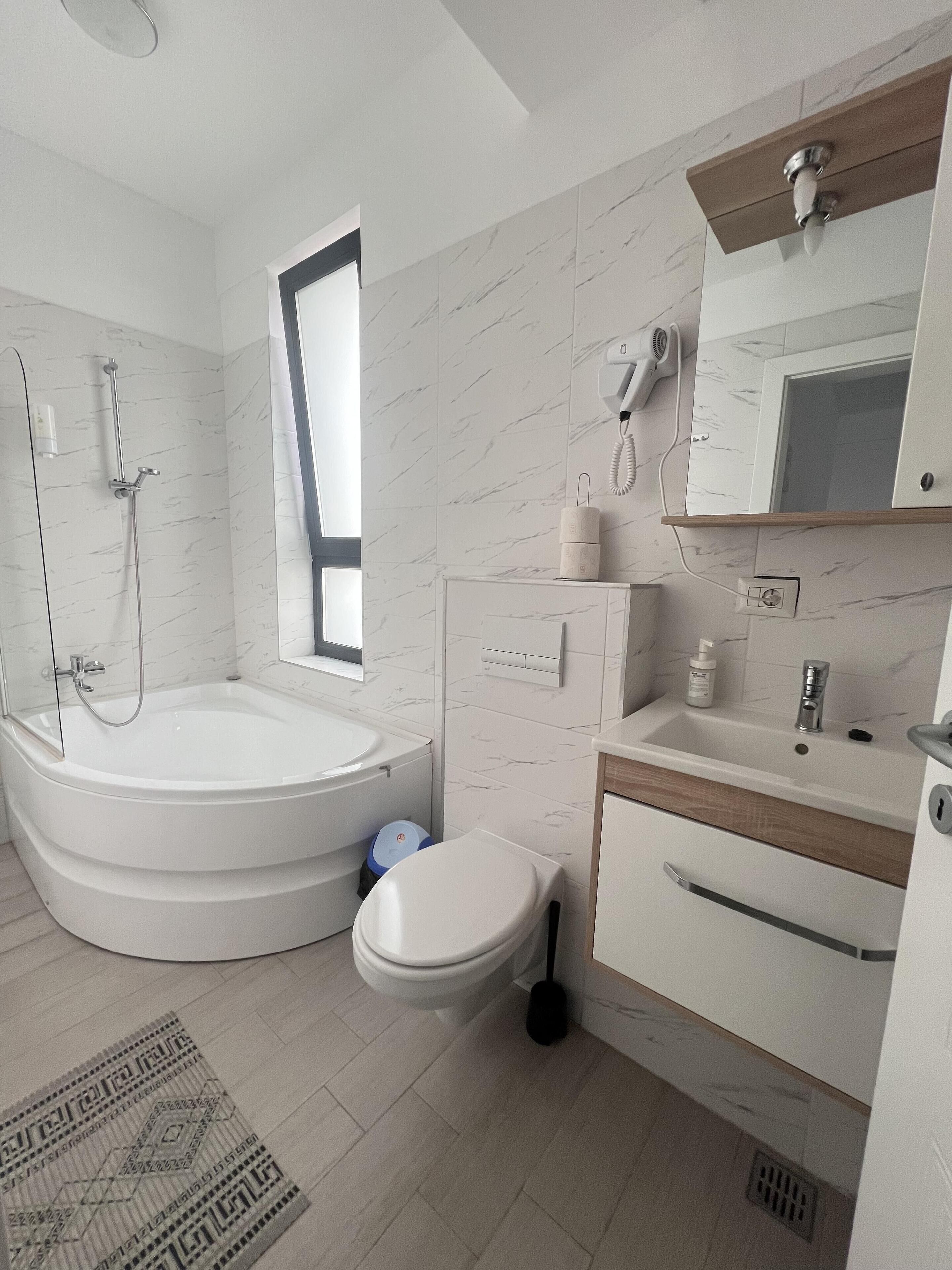 A modern bathroom with a bathtub, toilet, sink, and shower.