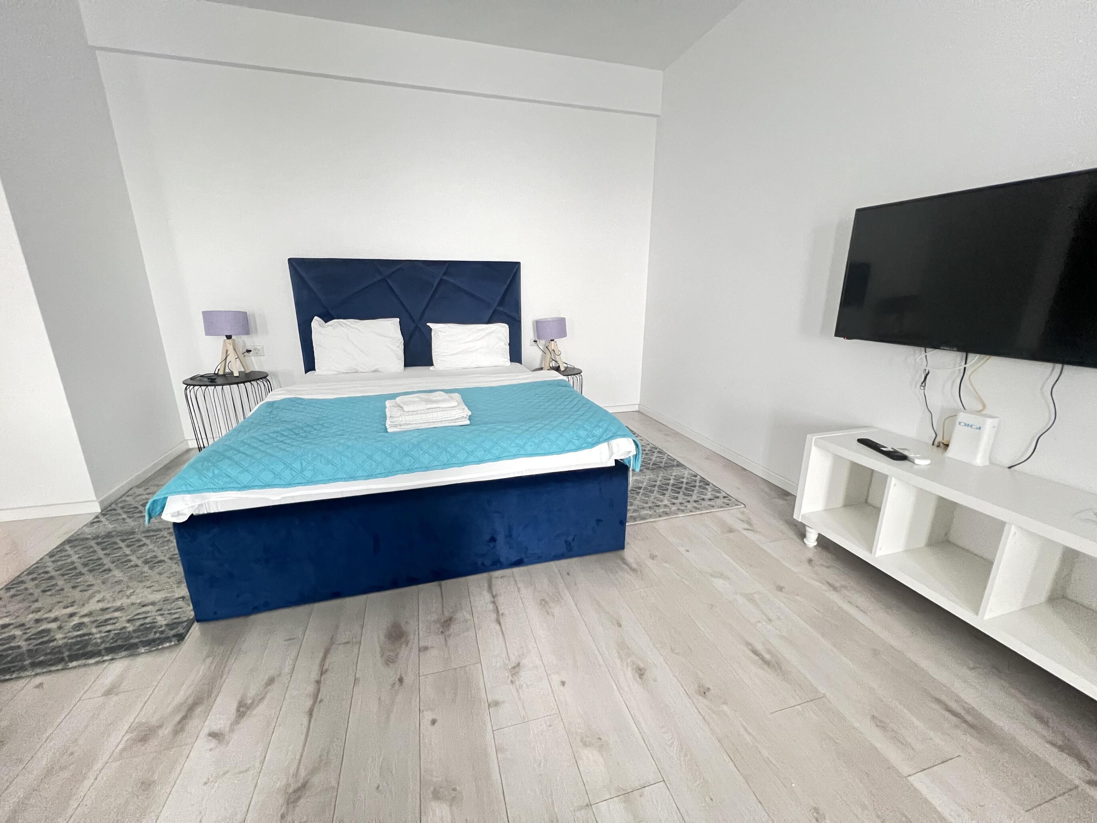 A modern bedroom with a large bed, a flat-screen TV, and a white console table.