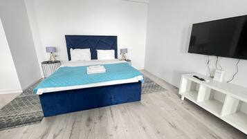A modern bedroom with a large bed, a flat-screen TV, and a white console table.