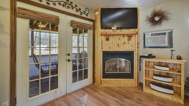 Ein Zimmer mit Kamin, einem darüber befestigten Fernseher und einer Holz-Unterhaltungsanlage.