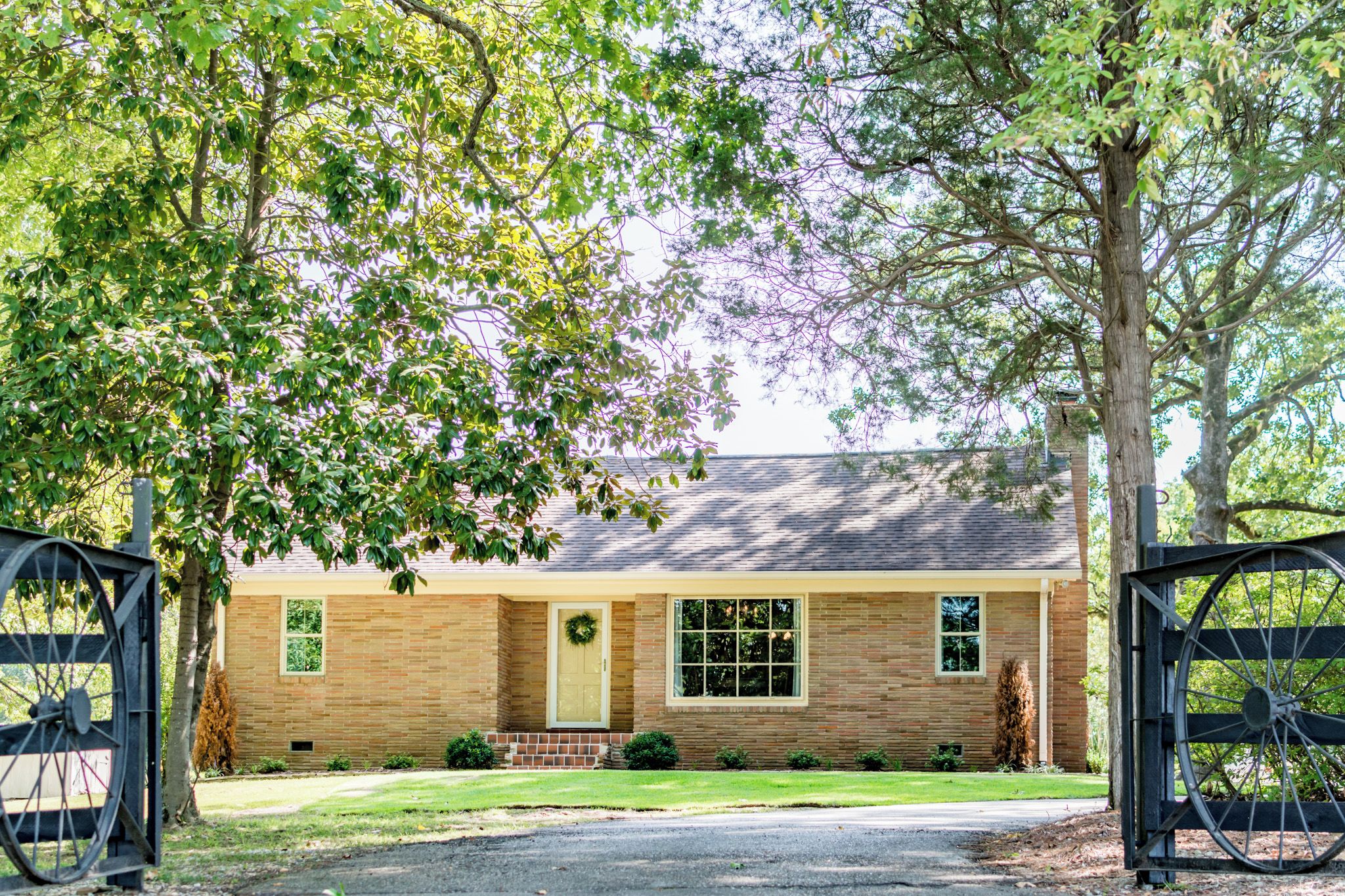 A brick house with a front door, a window, and a wreath on the door.