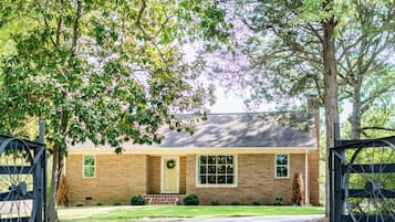 A brick house with a front door, a window, and a wreath on the door.