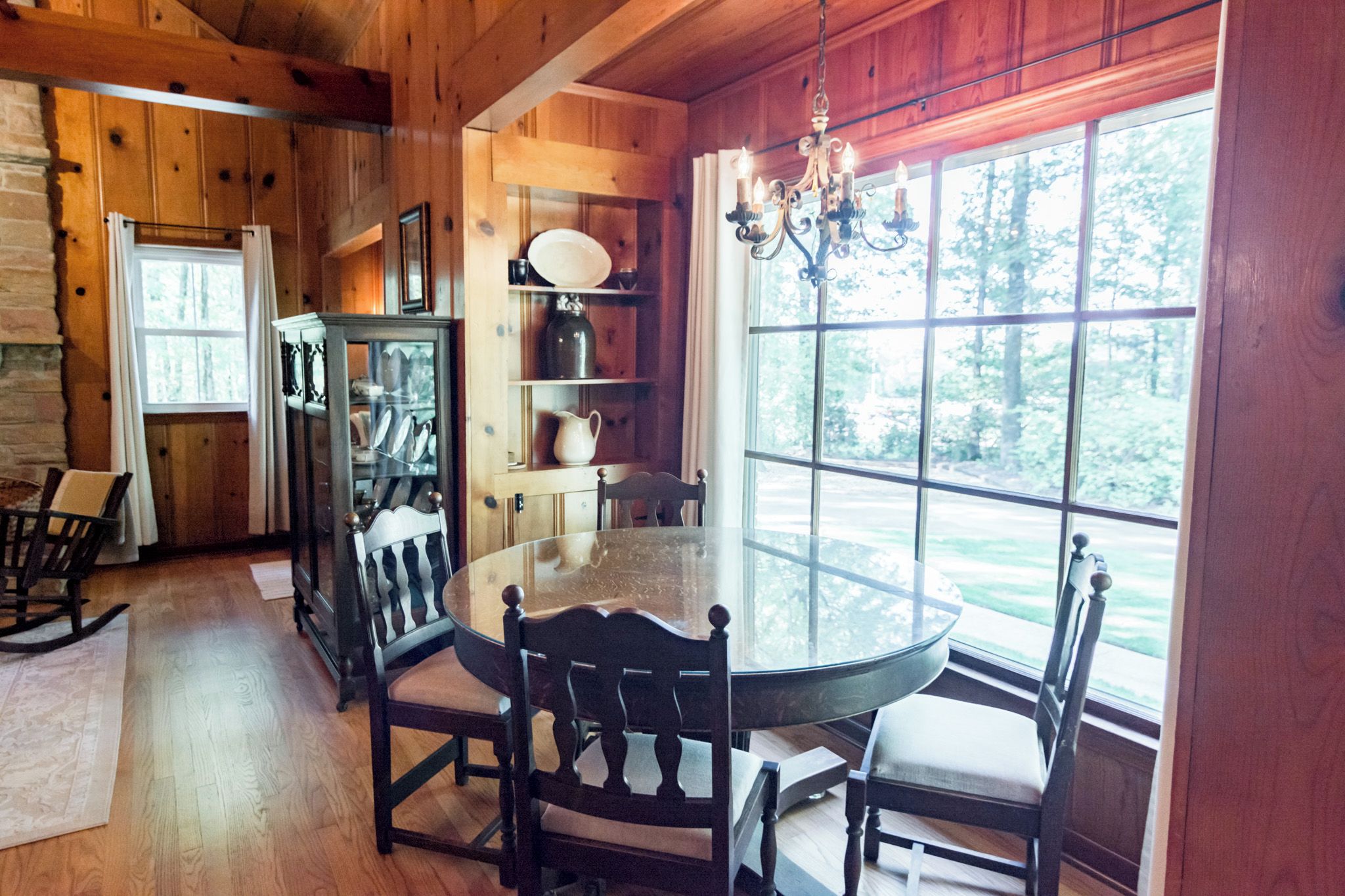 Une salle à manger en bois avec une table ronde, des chaises et un lustre.