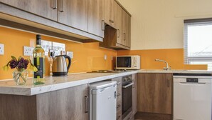 A kitchen with wooden cabinets, a microwave, a coffee maker, and a dishwasher.