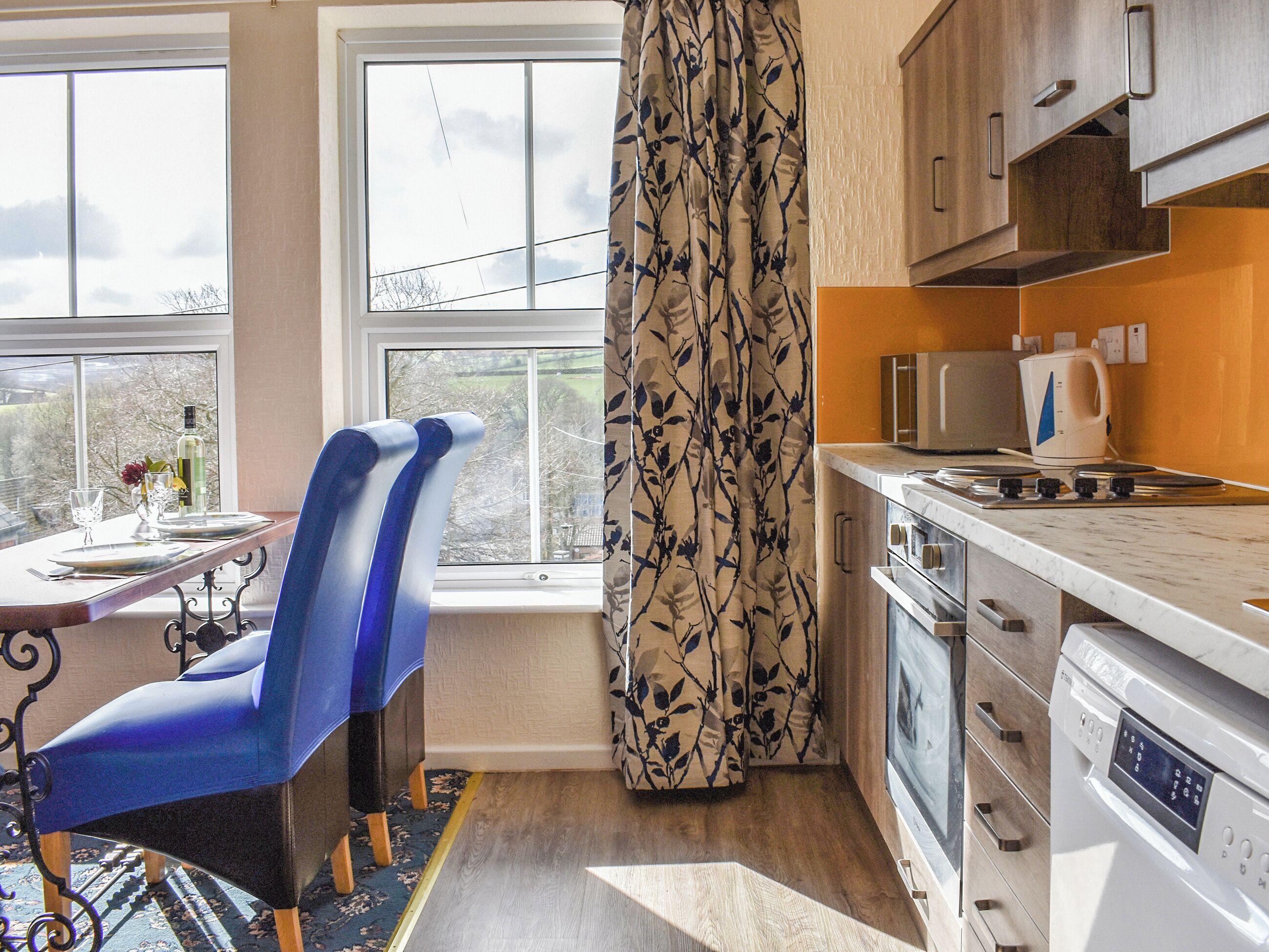 A modern kitchen with a dining area, a large window, and a view of the outdoors.