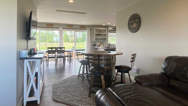 Un vaste espace de vie comprenant un canapé en cuir, une table à manger avec des chaises, un coin cuisine avec un bar et une grande fenêtre donnant sur l’extérieur.