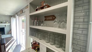 Une cuisine avec des meubles blancs, un plan de travail en marbre et un dosseret décoré d’un motif en briques.