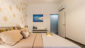Quarto com cama, mesa de cabeceira, pintura e ar condicionado.