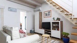 A modern living room with a sofa, a TV, a staircase, and a potted plant. - Baroque Apartments - Dentrortigia (Syracuse)