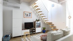 A modern living room with a staircase, a flat-screen TV, a sofa, and a small table. - Baroque Apartments - Dentrortigia (Syracuse)