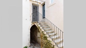 A narrow stone staircase with metal railings leading to a door with a metal grille. - Baroque Apartments - Dentrortigia (Syracuse)