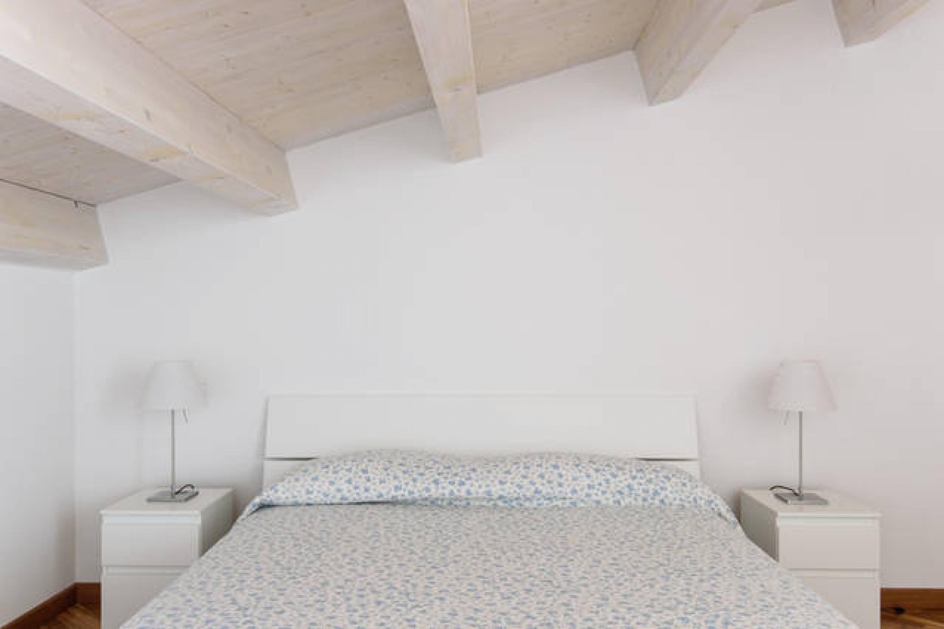 Een slaapkamer met een bed, twee nachtkastjes en een wit plafond.