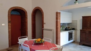 Una cucina compatta con mobili bianchi, una porta rossa e un arco in mattoni.