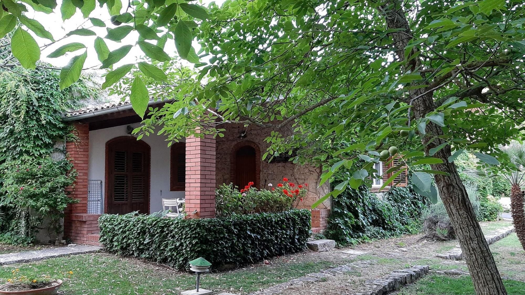 A traditional brick house with a covered porch, surrounded by lush greenery and a well-maintained garden.