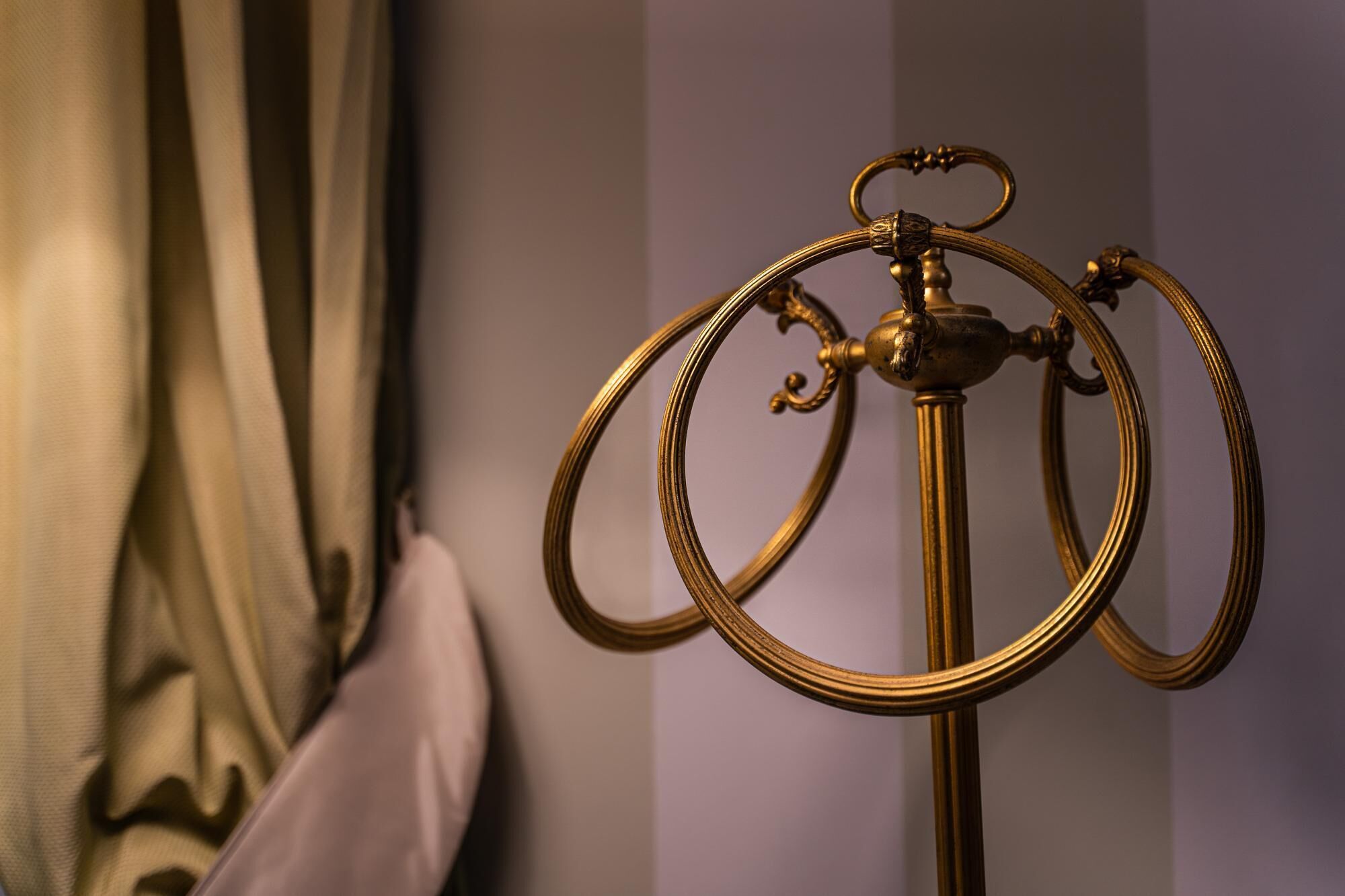 Eine messingfarbene Stehlampe mit gebogener Form und einem verzierten Knauf.