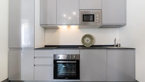 A modern kitchen with grey cabinets, a microwave, a stove, and a sink. - Capo 10 Liberty C3 in Siracusa (Syracuse)