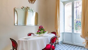 A dining area with a round table set for four, a large mirror above, and a view of a garden through a glass door. - Capo 10 Liberty C3 in Siracusa (Syracuse)