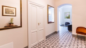 A hallway with a white door, a framed picture, a mirror, and a chair. - Capo 10 Liberty C3 in Siracusa (Syracuse)