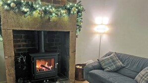 A cozy living room with a fireplace, a sofa, and a lamp. - 3 bedroom accommodation in Whatstandwell, near Matlock (Whatstandwell, near Matlock)