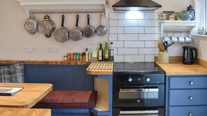 A kitchen with a stove, oven, hanging pots, and a variety of spices and condiments on the counter. - 3 bedroom accommodation in Whatstandwell, near Matlock (Whatstandwell, near Matlock)