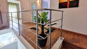 A modern interior with a staircase, a potted plant, and a contemporary painting.