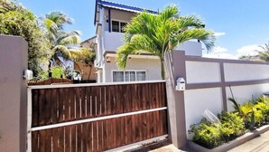 A gated residential area with a wooden fence, a white wall, and a palm tree.