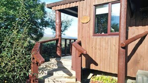 A wooden staircase leading to a covered porch with a window and a wooden sign.