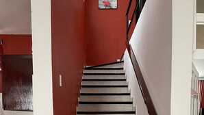 A staircase with black handrails and white walls, leading to a landing area with a kitchen counter and a window. - Casa a 5 Minutos del Hospital de La Mujer con Todos Los Servicios (Tehuacán)