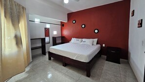 A bedroom with a bed, a ceiling fan, a red accent wall, and a mirror. - Casa a 5 Minutos del Hospital de La Mujer con Todos Los Servicios (Tehuacán)