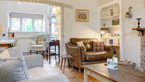 A cozy living room with a leather sofa, a wooden coffee table, and a dining area with a table and chairs.