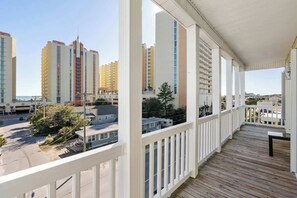 A balcony with a view of high-rise buildings and a parking area.
